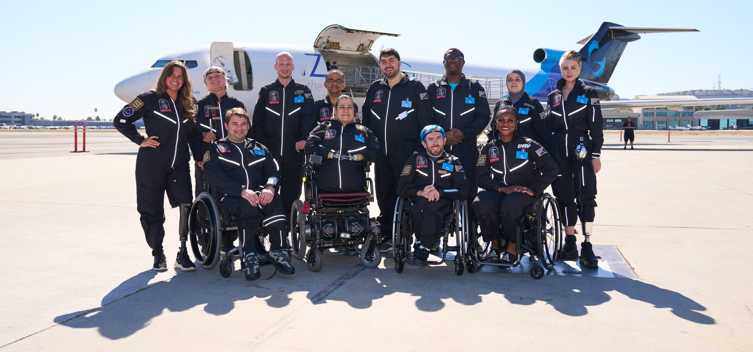A photo of the twelve astroaccess ambassadors, standing and smiling on a tarmac with the zero-g plane behind them.